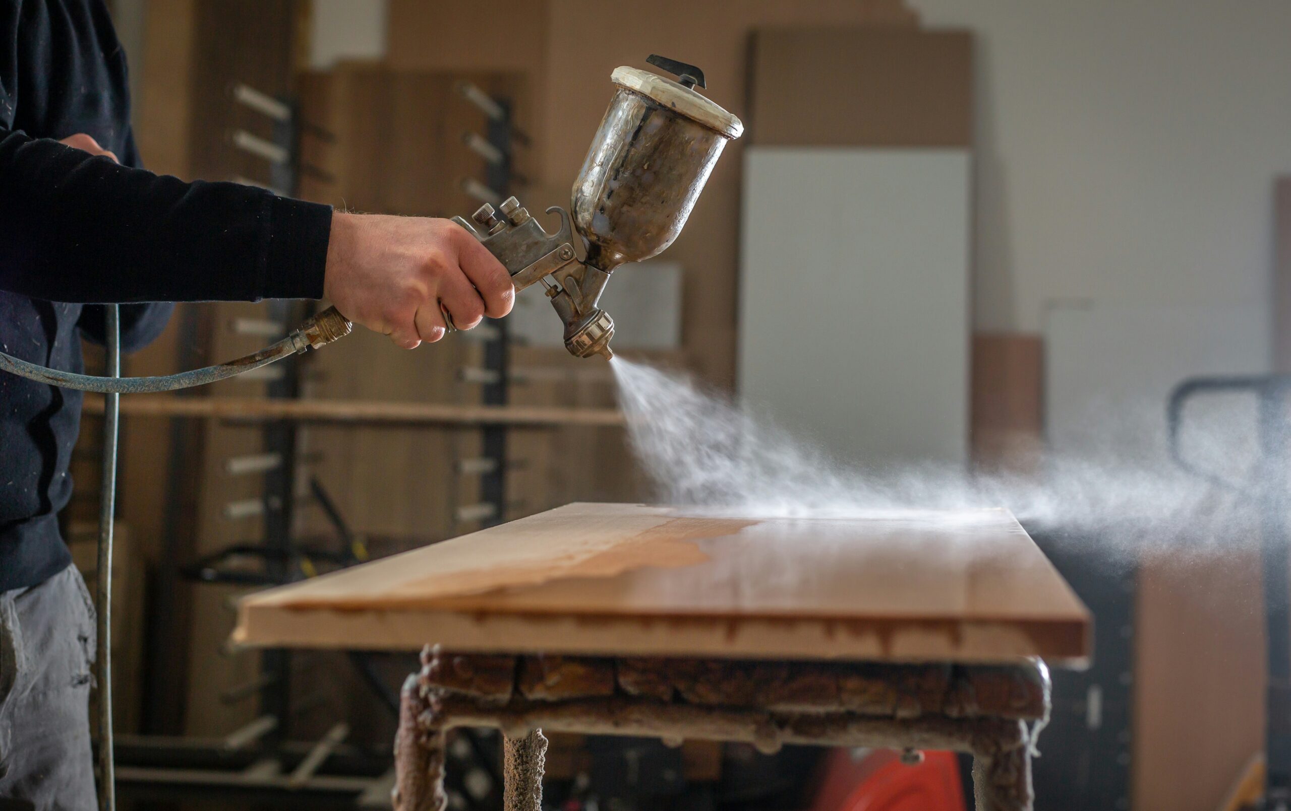 Wood panel in a spray room, mid way through being lacquered with a spray gun.